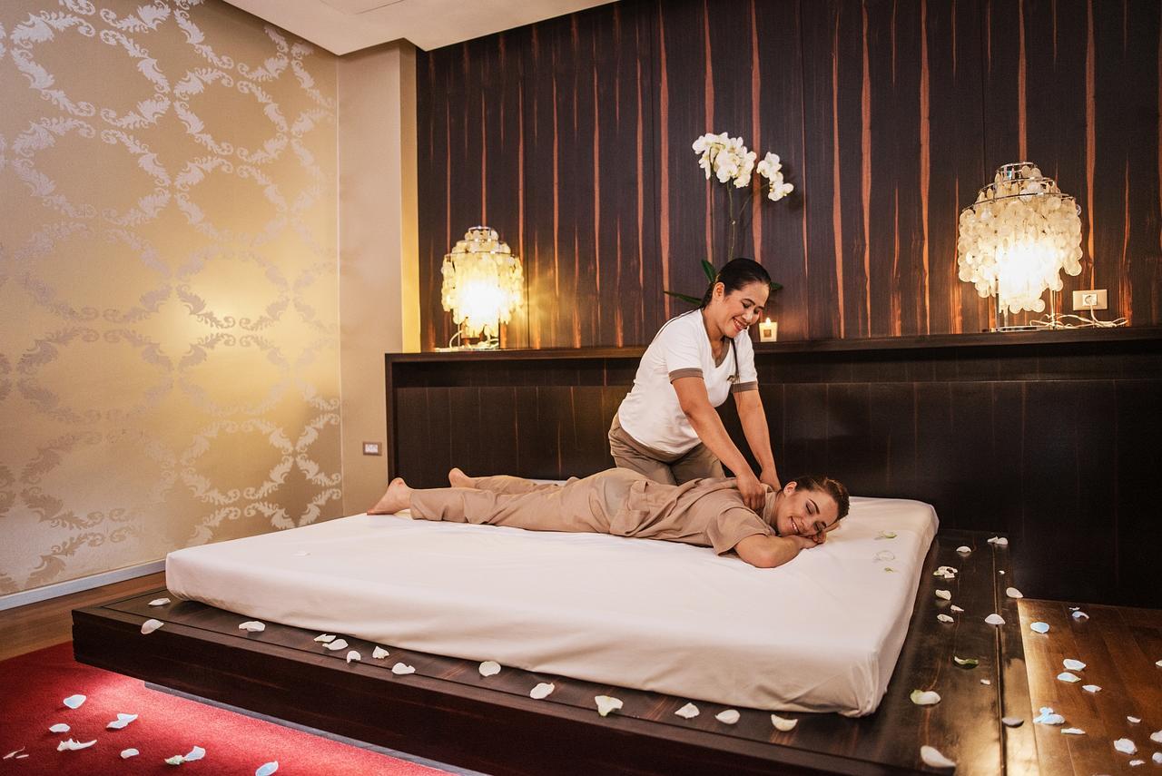 Grand Hotel Bernardin Portoroz Exterior photo The photo shows a relaxing spa setting where a massage therapist is performing a back massage on a client. The client is lying on a massage table, covered with a sheet and wearing a comfortable outfit. The room has a soothing ambiance, with warm ligh